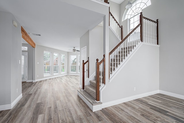staircase with visible vents, baseboards, ceiling fan, and wood finished floors