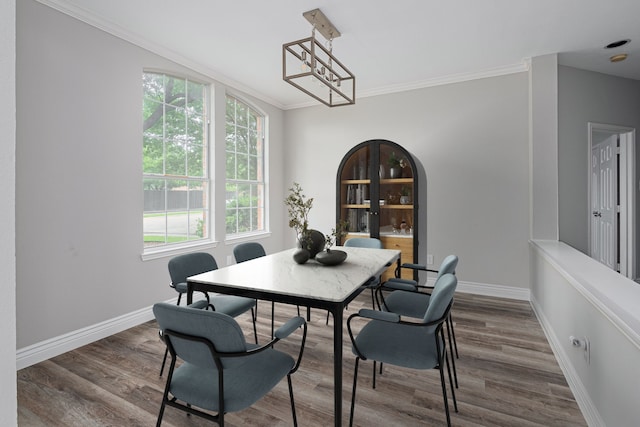 dining area featuring baseboards, ornamental molding, wood finished floors, and a notable chandelier