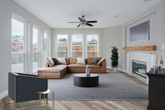 living room featuring a ceiling fan, a fireplace with flush hearth, plenty of natural light, and wood finished floors