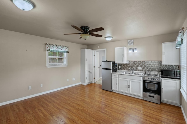 2311 Cedar Cir, Granbury, TX 76048 - kitchen with appliances with stainless steel finishes, a sink, ceiling fan, white cabinets, and light wood-style flooring
