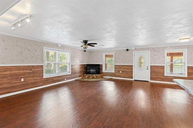 2311 Cedar Cir, Granbury, TX 76048 - unfurnished living room featuring a wainscoted wall, a textured ceiling, plenty of natural light, hardwood / wood-style floors, and wood walls