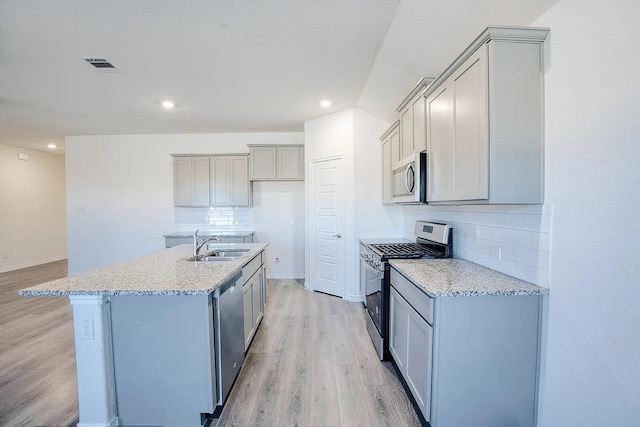 kitchen with decorative backsplash, a sink, stainless steel appliances, recessed lighting, and light wood-style flooring