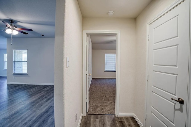 hall featuring baseboards, dark wood-style floors, and visible vents