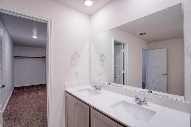 bathroom featuring a sink, a spacious closet, double vanity, and visible vents