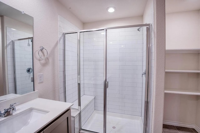 full bathroom with vanity, a textured wall, a stall shower, and tile patterned floors