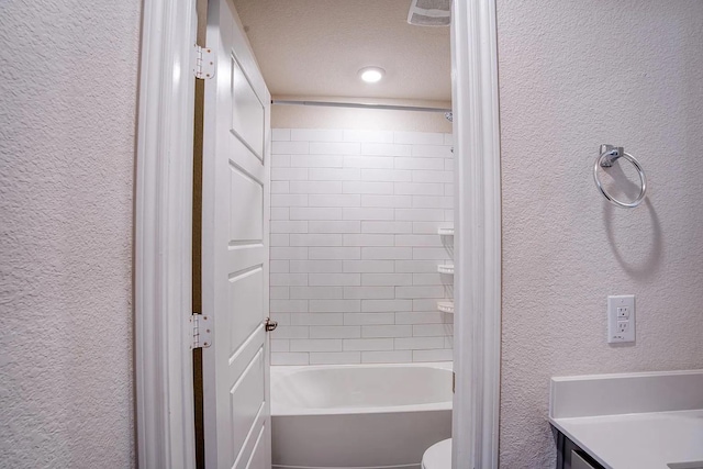 full bath with vanity, a textured wall, and shower / bathing tub combination