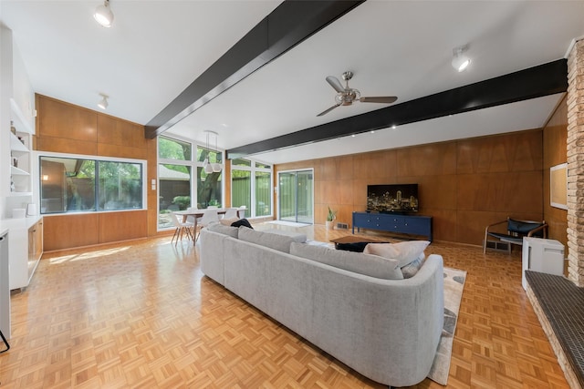 living room with wooden walls, ceiling fan, and lofted ceiling with beams