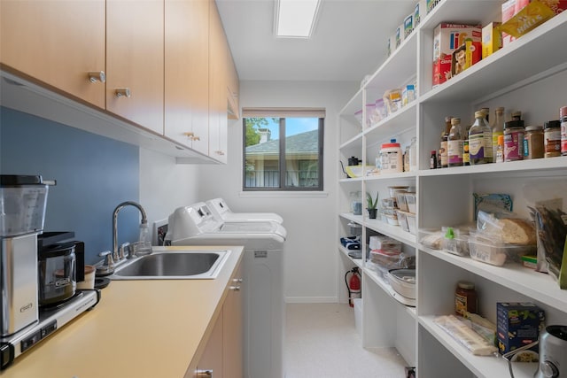 clothes washing area with baseboards, a sink, cabinet space, and washing machine and dryer