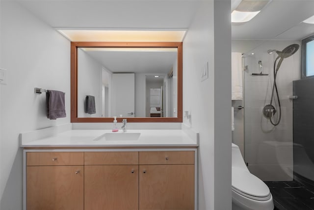 bathroom with toilet, a tile shower, and vanity