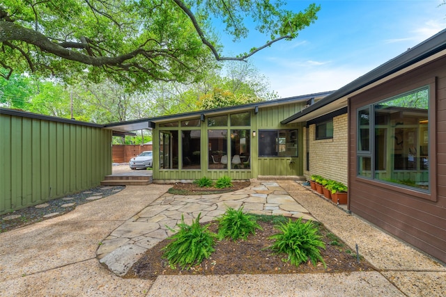 exterior space with a patio, a sunroom, and brick siding