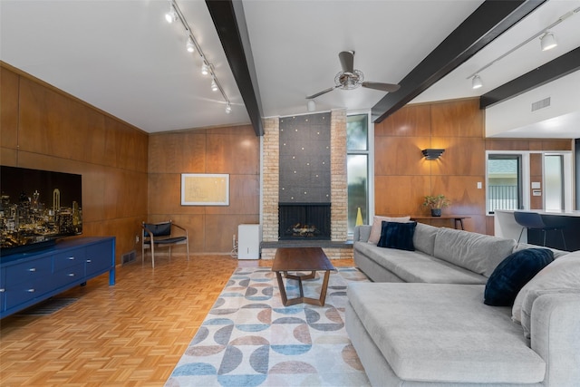 living area with rail lighting, visible vents, wood walls, and beam ceiling