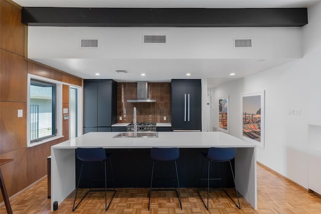 kitchen featuring wall chimney range hood, built in refrigerator, visible vents, and modern cabinets