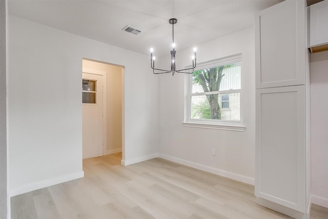 unfurnished dining area with visible vents, light wood-style floors, baseboards, and an inviting chandelier