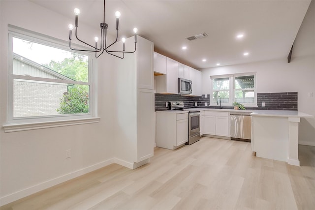 kitchen with visible vents, a sink, light wood finished floors, appliances with stainless steel finishes, and backsplash