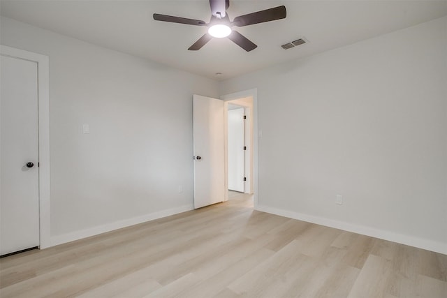 empty room featuring light wood-type flooring, a ceiling fan, baseboards, and visible vents
