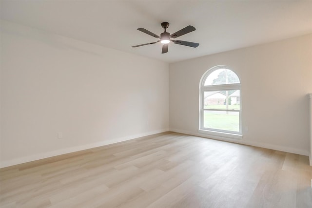 empty room featuring a ceiling fan, baseboards, and light wood finished floors