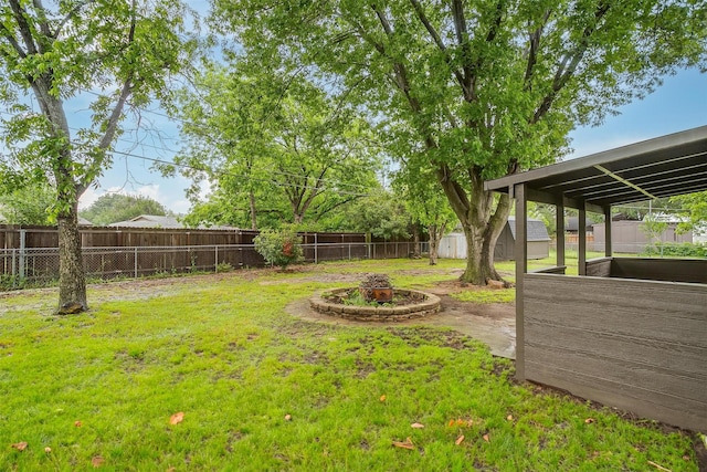 view of yard featuring an outdoor structure, a fenced backyard, a fire pit, and a shed
