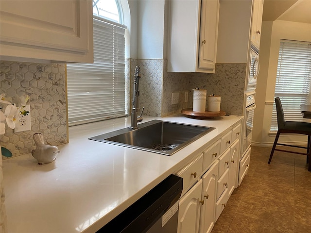 kitchen with decorative backsplash, a sink, light countertops, white appliances, and white cabinetry