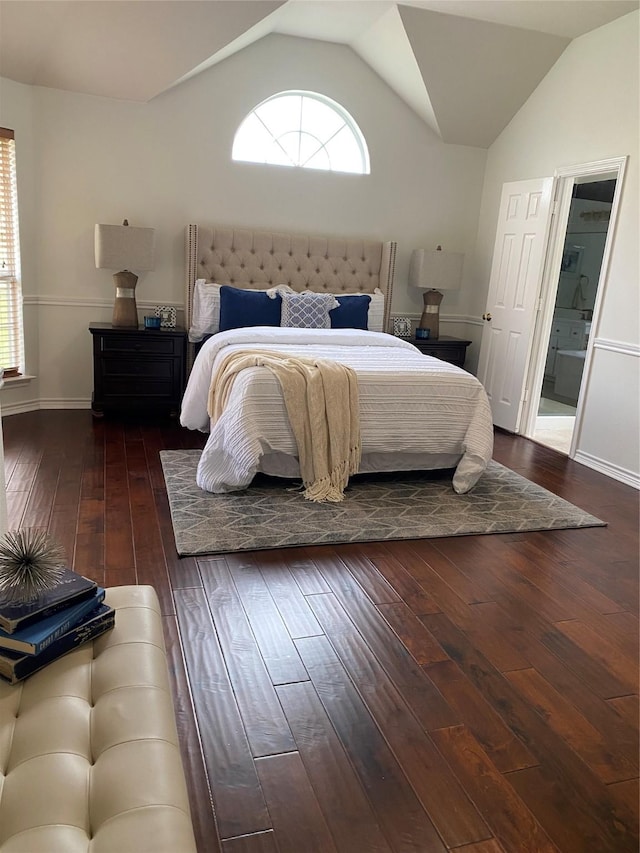 bedroom with wood-type flooring, connected bathroom, baseboards, and lofted ceiling