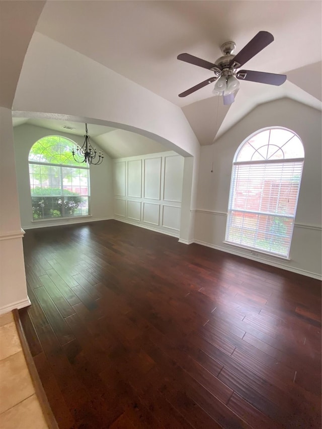 unfurnished room with baseboards, ceiling fan with notable chandelier, vaulted ceiling, and hardwood / wood-style floors