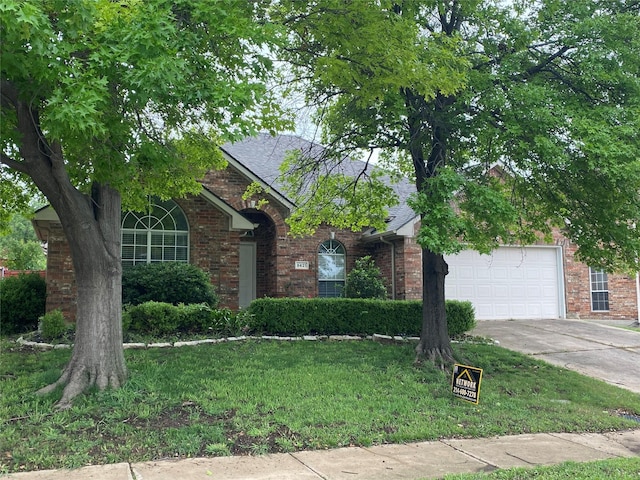 view of front of house featuring a front yard, roof with shingles, brick siding, concrete driveway, and an attached garage