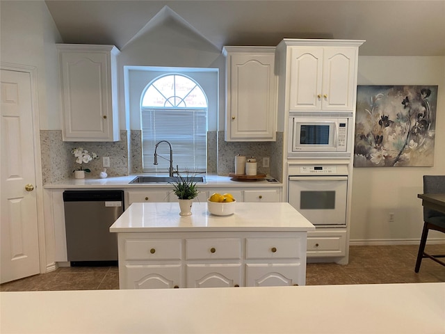 kitchen with a sink, white cabinetry, white appliances, and tasteful backsplash
