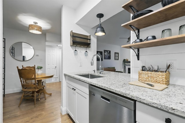 kitchen featuring light stone countertops, open shelves, dishwasher, a sink, and light wood-style floors