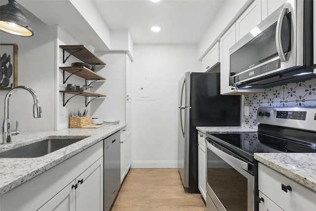 kitchen with backsplash, open shelves, a sink, white cabinets, and stainless steel appliances