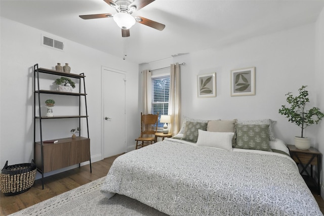 bedroom with baseboards, ceiling fan, wood finished floors, and visible vents