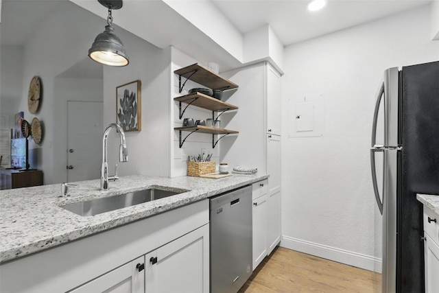kitchen with open shelves, light stone countertops, a sink, stainless steel appliances, and light wood-type flooring