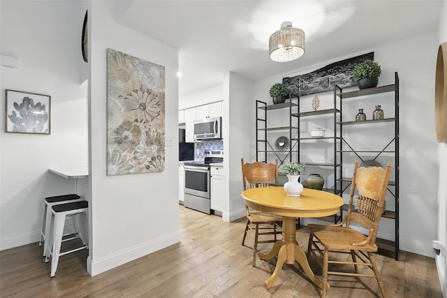 dining space with baseboards and light wood finished floors
