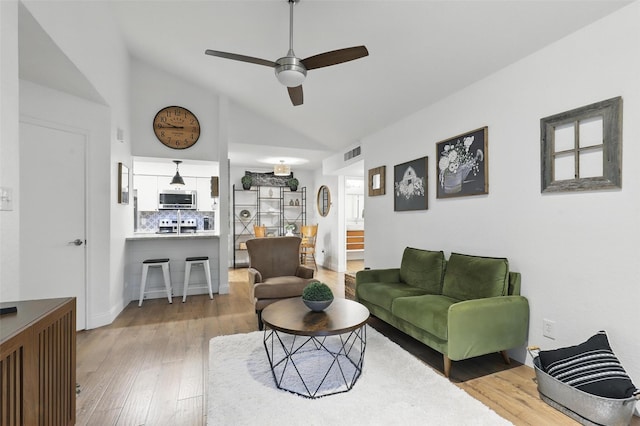 living area with visible vents, a ceiling fan, lofted ceiling, and hardwood / wood-style floors