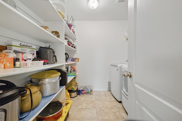 storage area with visible vents and washing machine and clothes dryer