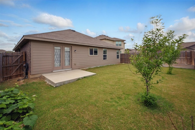 rear view of house featuring a lawn, a fenced backyard, and french doors