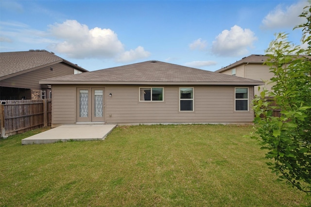 rear view of property featuring fence, a patio, a yard, and roof with shingles
