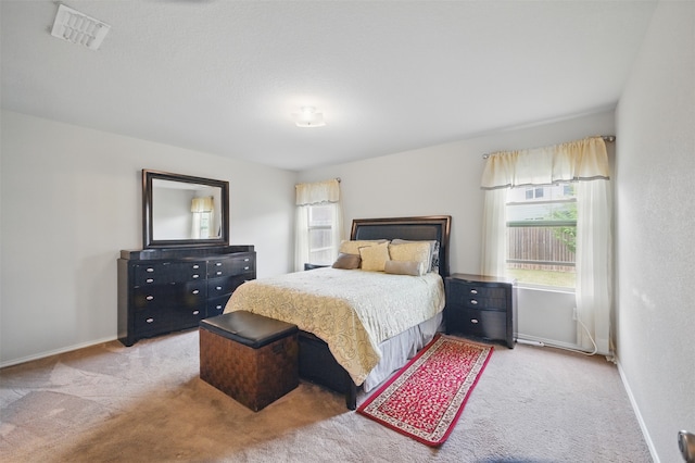 bedroom featuring baseboards, light colored carpet, and visible vents