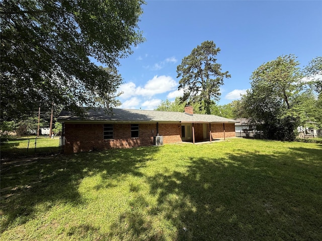 290 Dickard St, Hawkins, TX 75765 - back of property featuring fence, a chimney, brick siding, central AC unit, and a lawn