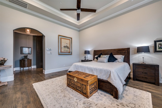 bedroom with visible vents, ornamental molding, a raised ceiling, arched walkways, and dark wood finished floors