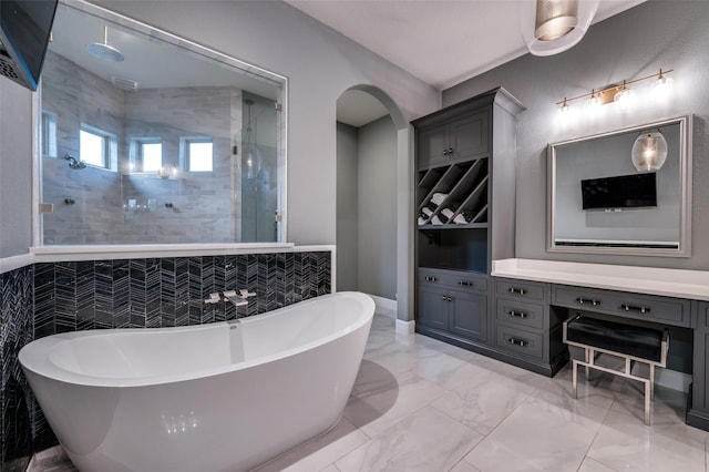 bathroom featuring vanity, marble finish floor, a freestanding tub, and a tile shower