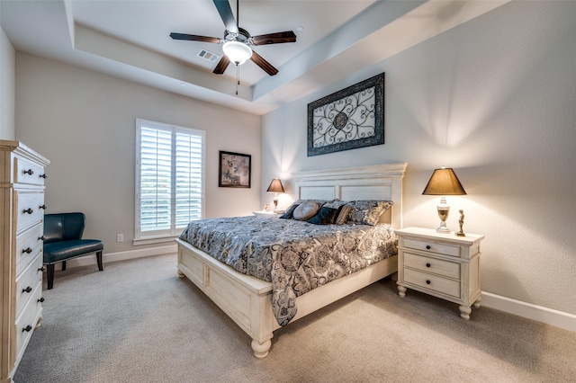 bedroom with light colored carpet, baseboards, visible vents, and a raised ceiling