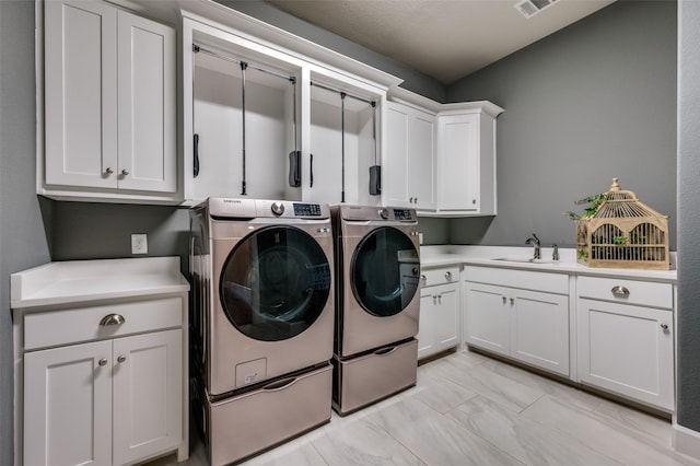 washroom featuring independent washer and dryer, cabinet space, a sink, marble finish floor, and visible vents