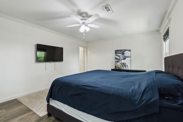 bedroom featuring a ceiling fan, visible vents, crown molding, wood finished floors, and baseboards