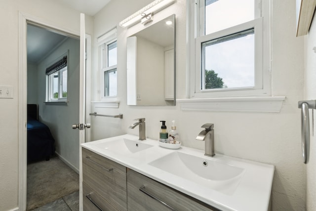 full bathroom with double vanity, baseboards, and a sink