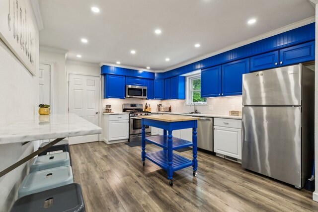 kitchen with crown molding, dark wood-style flooring, tasteful backsplash, a sink, and appliances with stainless steel finishes