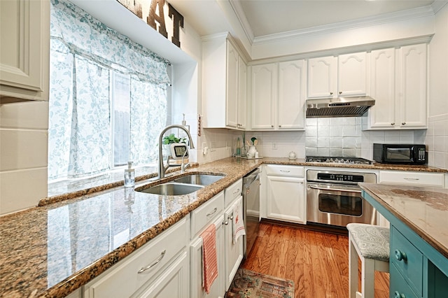 kitchen with wood finished floors, white cabinetry, under cabinet range hood, a sink, and appliances with stainless steel finishes