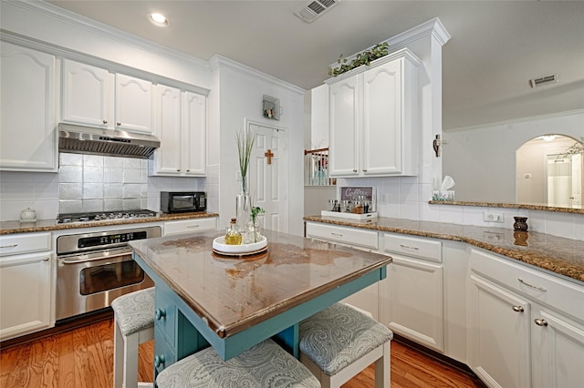 kitchen featuring under cabinet range hood, stainless steel appliances, visible vents, and ornamental molding