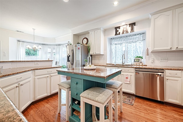 kitchen featuring a notable chandelier, a sink, light wood-style flooring, stainless steel appliances, and tasteful backsplash