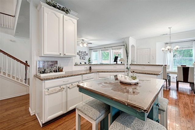 kitchen with white cabinets, a peninsula, and wood finished floors