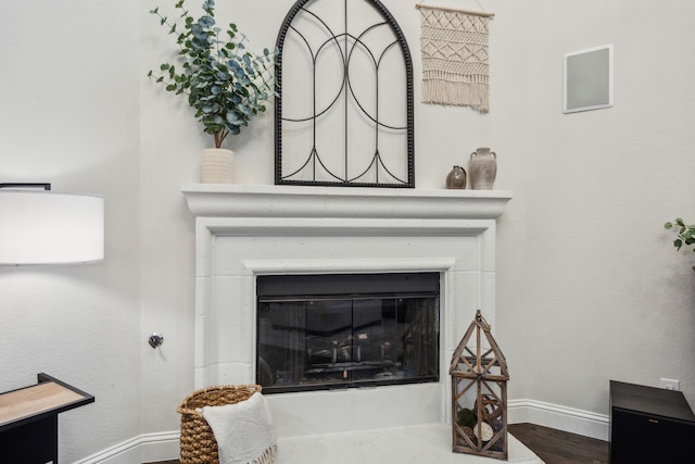 details featuring a glass covered fireplace, baseboards, and wood finished floors
