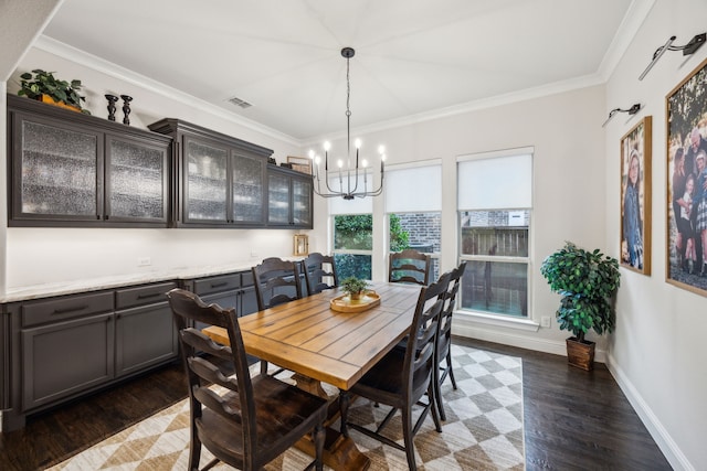dining room with an inviting chandelier, ornamental molding, wood finished floors, and visible vents